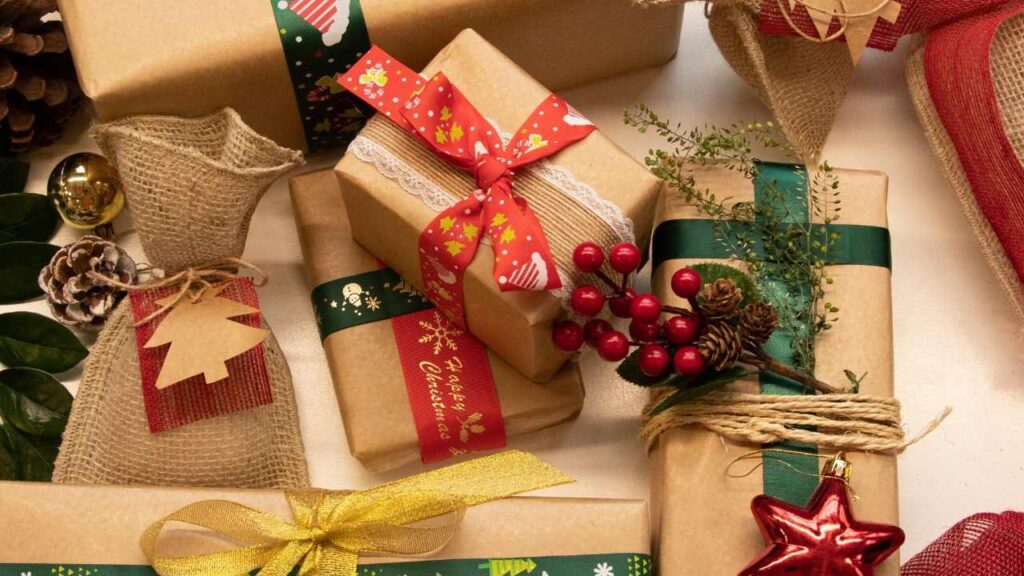 mesa com presentes natalinos, caixas e sacolas de presente, decoração natalina