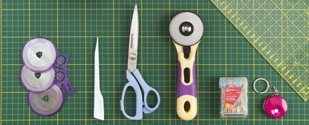 Imagem ilustrativa de ferramentas essenciais para costura: tesoura, cortador circular, régua, fita métrica e fita métrica.