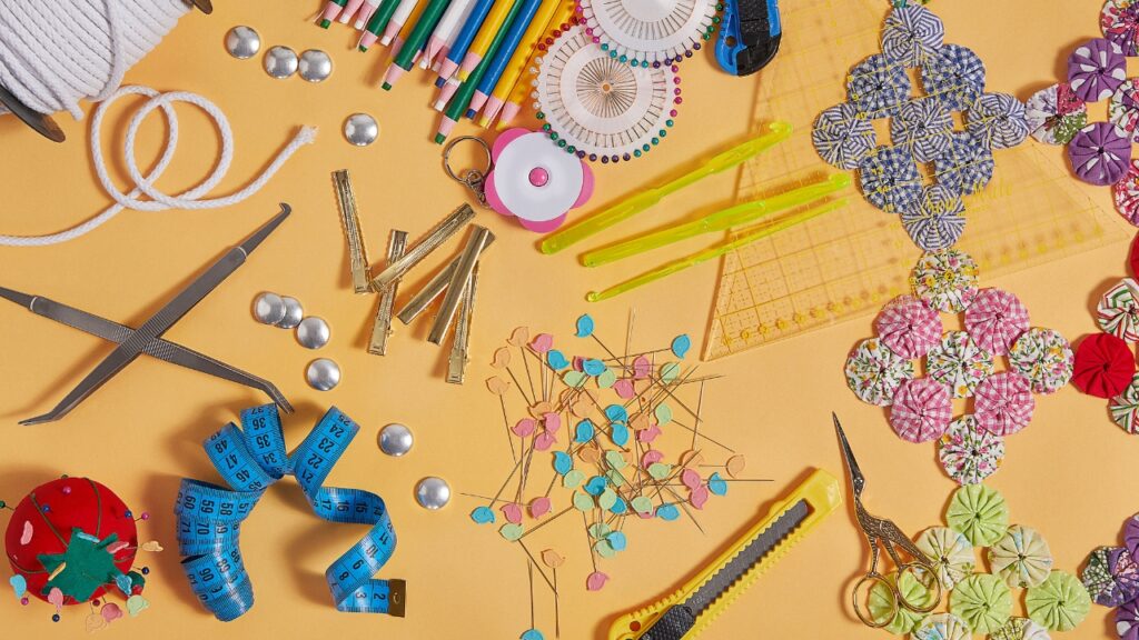 Um espaço de costura bem organizado, repleto de diversos materiais de costura, incluindo bobinas de linha, tesouras, agulhas, fita métrica, retalhos de tecido e moldes de costura.