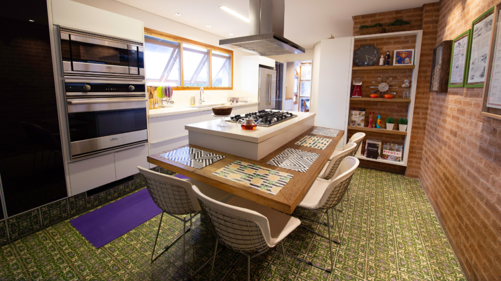 Imagem geral de uma cozinha com mesa em ilha. No balcão, jogos americanos enfeitam a mesa.