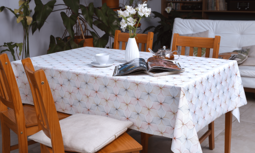 Uma mesa de jantar elegantemente decorada. A mesa é coberta por uma toalha de mesa de linho branca e adornada com um arranjo de flores. Um livro aberto completa a cena.